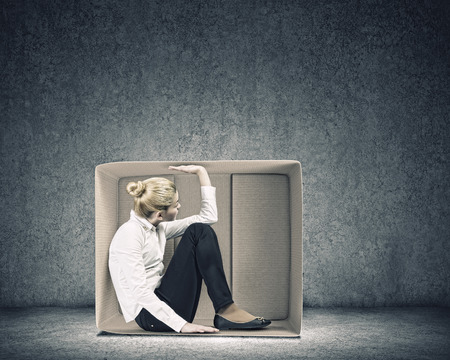 Young businesswoman trapped in carton boxの写真素材