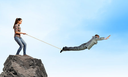 Woman holding on rope businessman trying to escape