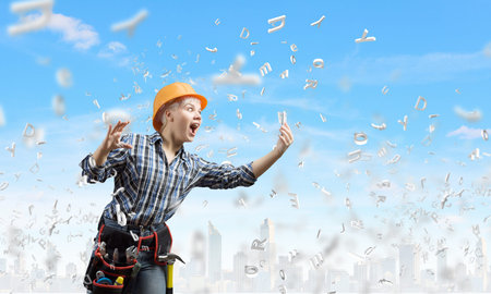 Young woman builder screaming emotionally in mobile phoneの写真素材