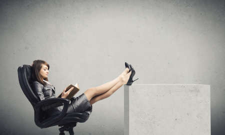 Young attractive businesswoman reading book in chairの写真素材