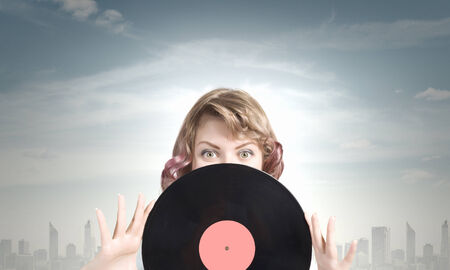 Young woman in casual wearing headphones and holding disco plateの写真素材