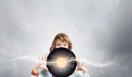 Young woman in casual wearing headphones and holding disco plateの写真素材