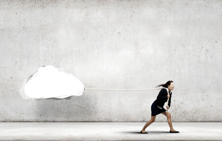 Young businesswoman pulling white cloud with ropeの写真素材