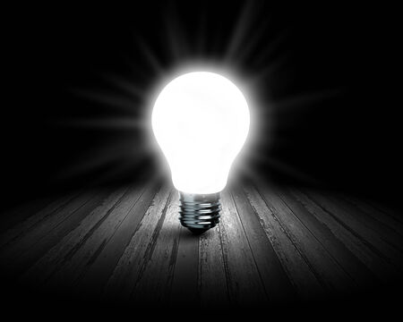 Background image with glowing light bulb on wooden surfaceの写真素材