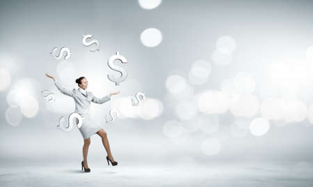 Young pretty businesswoman juggling with dollar symbolsの写真素材