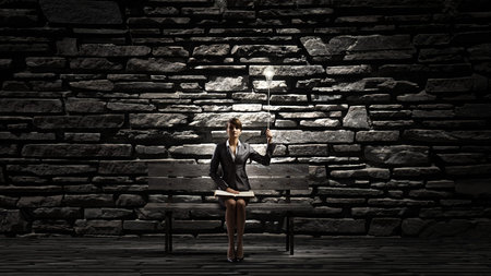 Young smiling businesswoman sitting on bench with book in handsの写真素材