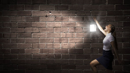 Young businesswoman walking in darkness with lantern in handの写真素材