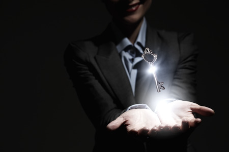 Close up of businesswoman holding golden key in handの写真素材