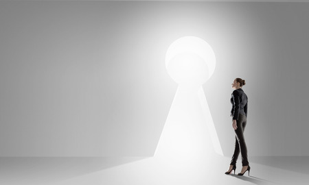 Back view of businesswoman standing in keyhole doorwayの写真素材