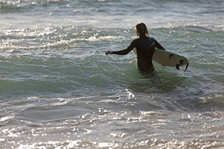 A surfer with his surfboard at the beachの写真素材