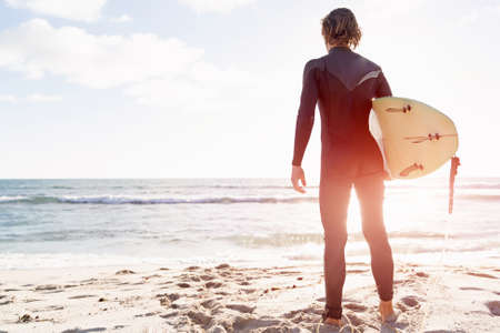 A surfer with his surfboard at the beachの写真素材