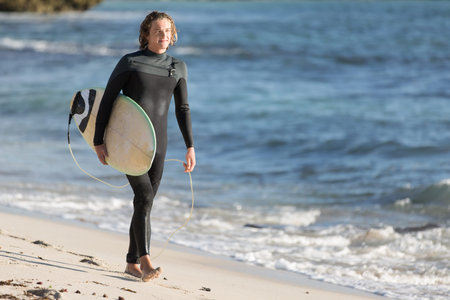 A surfer with his surfboard at the beachの写真素材