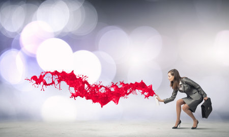 Businesswoman spraying colorful paint splashes from container