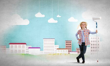 Cute girl of school age painting wall with rollerの写真素材