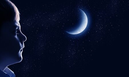 Cute boy of school age against night backgroundの写真素材