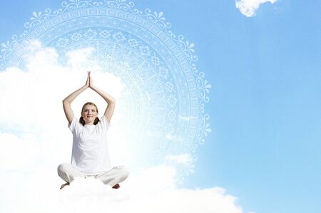 Young smiling girl sitting on cloud and meditatingの写真素材