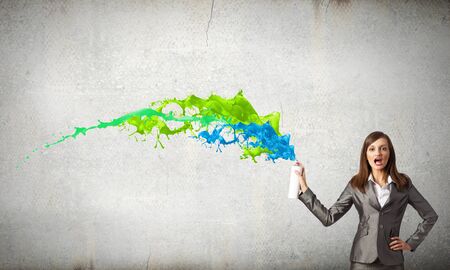 Businesswoman spraying colorful paint splashes from containerの写真素材