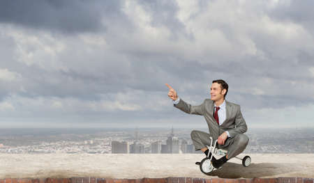 Young handsome businessman riding three wheeled bicycleの写真素材