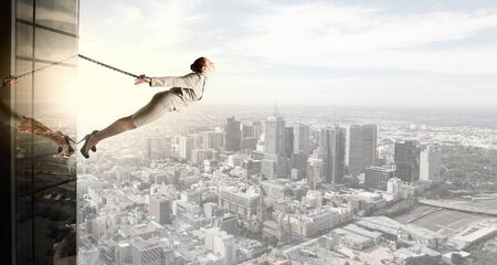 Young businesswoman with ropes on hands trying to flyの写真素材