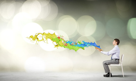 Businessman sitting in chair and reading bookの写真素材