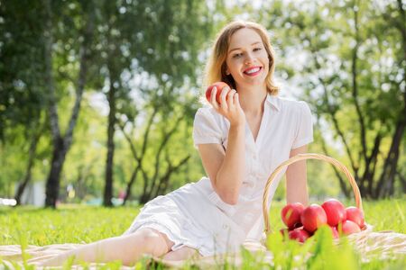 Young pretty woman in summer park with appleの写真素材