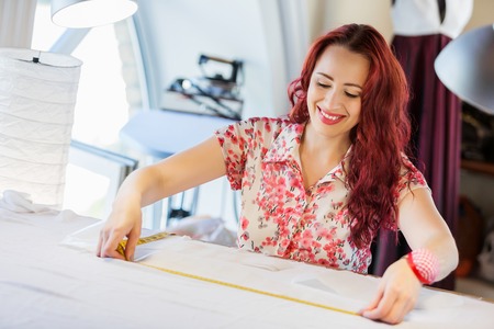Pretty dressmaker at work making patterns of fabricの写真素材
