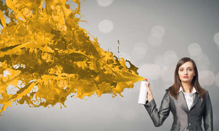 Businesswoman spraying colorful paint splashes from containerの写真素材