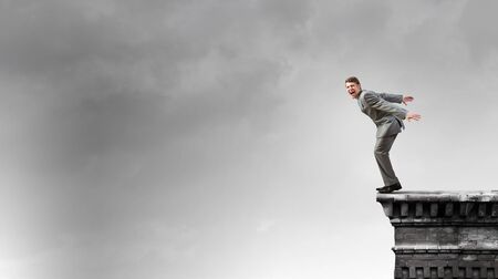 Determined businessman jumping in deep from edge of buildingの写真素材