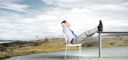 Businessman sitting in chair with legs on table and relaxingの写真素材