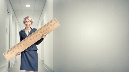 Young businesswoman measuring something with big rulerの写真素材