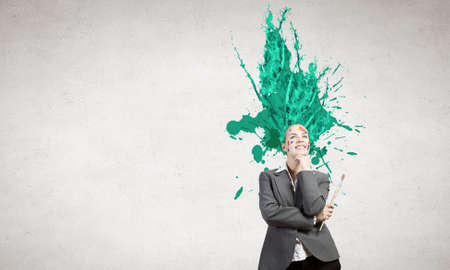 Thoughtful businesswoman with colorful splashes out of her headの写真素材