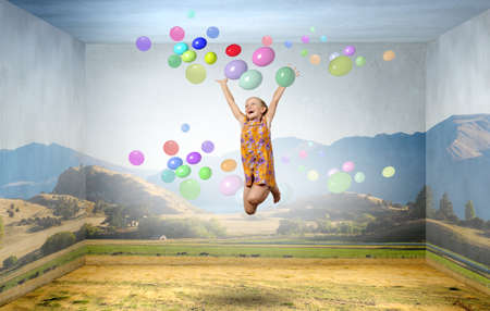 Little cute girl jumping high and flying in skyの写真素材