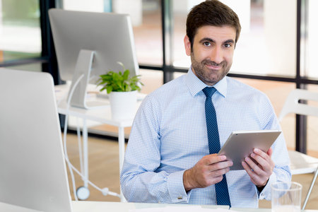 Handsome businessman with tablet in office