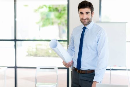 Young businessman in office standing with papers in his handsの写真素材