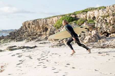 A surfer with his surfboard at the beachの写真素材