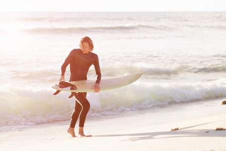 A surfer with his surfboard at the beachの写真素材