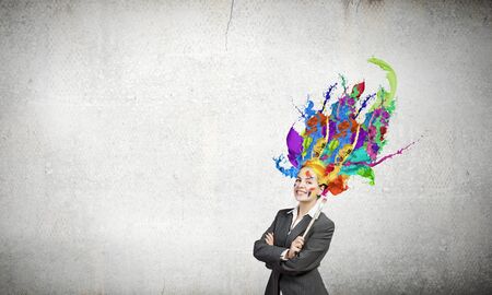 Thoughtful businesswoman with colorful splashes out of her headの写真素材