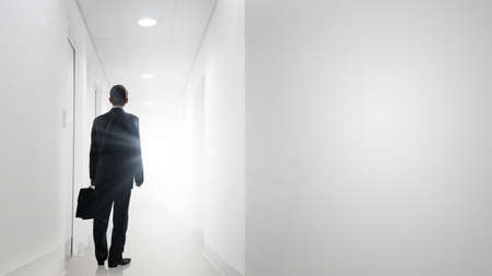 Rear view of businessman walking in office corridorの写真素材