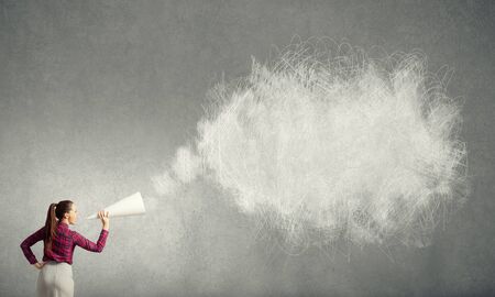 Young pretty woman screaming in paper trumpetの写真素材