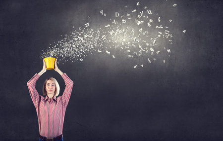 Young blond woman with yellow bucket in handsの写真素材