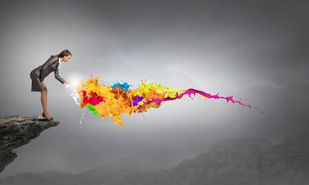 Businesswoman spraying colorful paint splashes from containerの写真素材