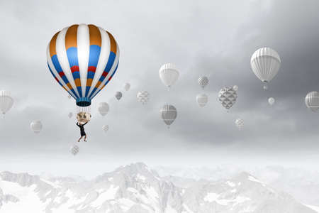 Businesswoman flying on aerostat balloon high in skyの写真素材