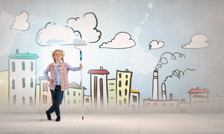Cute girl of school age painting wall with rollerの写真素材
