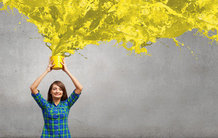 Young girl in casual splashing colorful paint from bucket