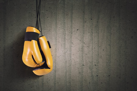 Pair of yellow boxing gloves hanging on allの写真素材