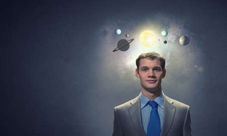 Young businessman and planets of space spinning aroundの写真素材