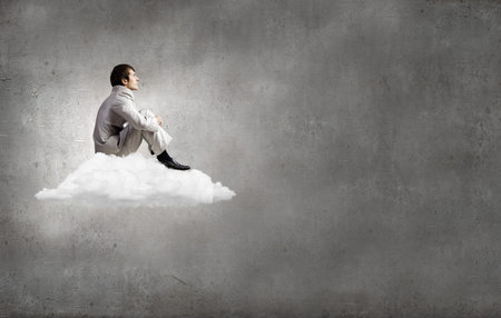 Young businessman sitting on cloud and relaxing