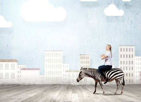 Young pretty fearless woman riding zebra animalの写真素材