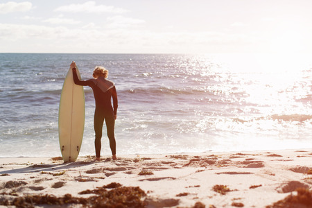 A surfer with his surfboard at the beachの写真素材