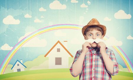 Funny cute boy trying on paper mustacheの写真素材